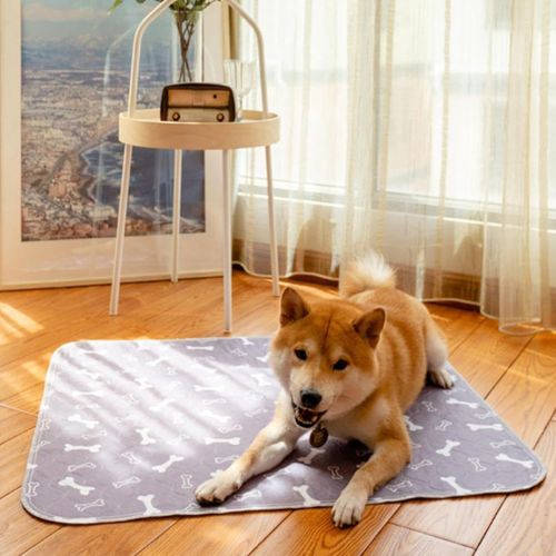 Un Shiba-Inu allongé confortablement sur alèse pour chien gris étanche posé sur le sol en parquet