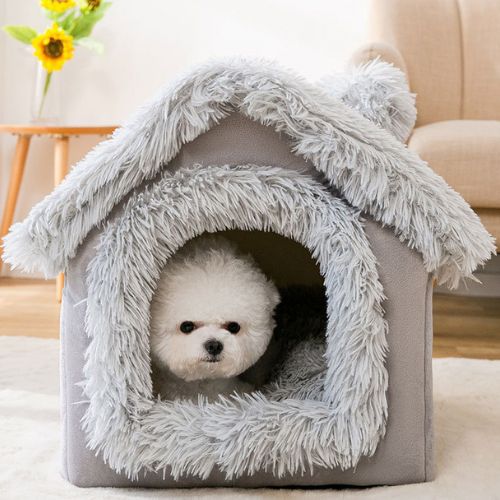Petit chien blanc installé dans une cabane pour chien grise en tissu doux, avec toit en fausse fourrure, offrant un refuge apaisant et chaleureux pour chiens anxieux ou stressés
