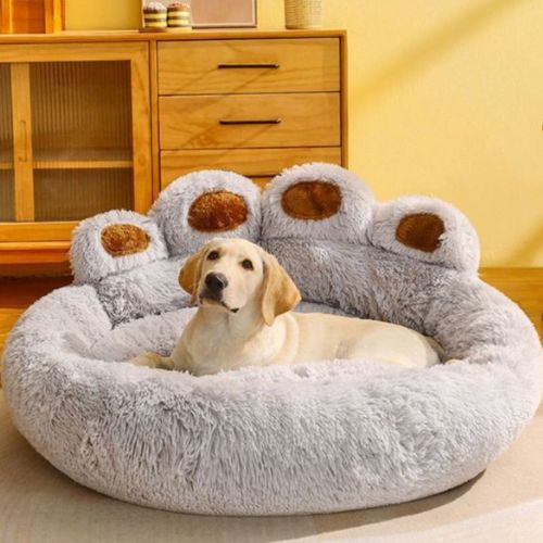 Un grand Labrador blanc détendu assis dans un coussin pour chien en forme de patte, ultra doux et réconfortant, couleur gris.