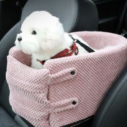 Lit pour chien rose avec attache harnais intégré, placé sur un siège de voiture pour assurer confort et sécurité pendant les déplacements