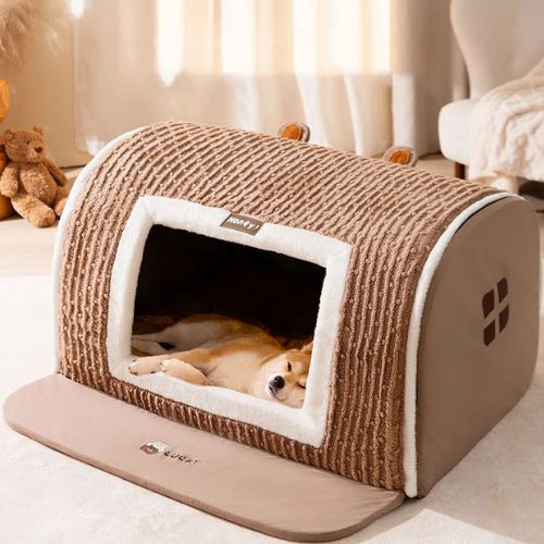 Un Shiba Inu couché confortablement dans une niche chien interieur beige et marron, en forme de maisonnette.