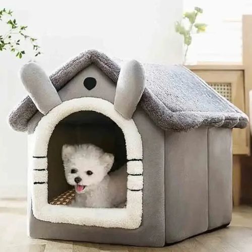 Petit chien blanc installé confortablement dans une niche d'intérieur pour chien grise doux au toucher.