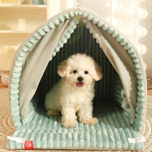 Petit chien blanc assis tranquillement à l'intérieur d'une niche pour chien douillet avec rideau coupe vent de couleur kaki avec tissu en velours vert doux.