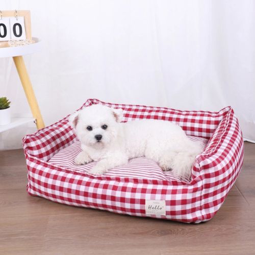 Petit chien couché dans un panier pour chien moelleux en tissu vichy rouge, placé dans un intérieur lumineux
