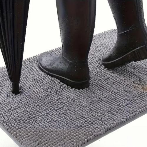 tapis pour chien devant la porte d'entrée étanche et imperméable ultra absorbant une personne chaussée une botte plastique et une parapluie à la main.