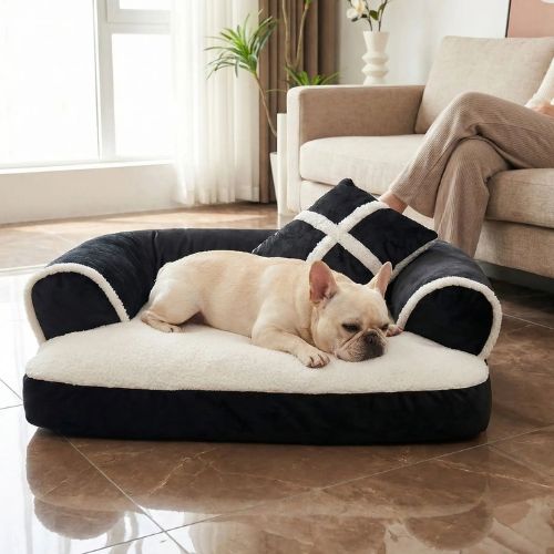 Un Bouledogue Français dort paisiblement sur un canapé pour chien confortable couleur noir, posé dans un salon lumineux.