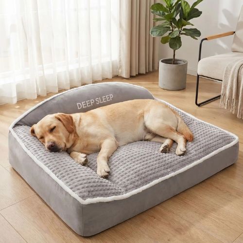 Un Labrador Retriever dort sur un lit pour chien gris déhoussable et doux posé dans une pièce lumineuse.