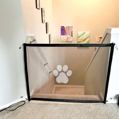 Barrière chien noire en tissu mesh avec empreinte blanche protégeant l’accès aux escaliers