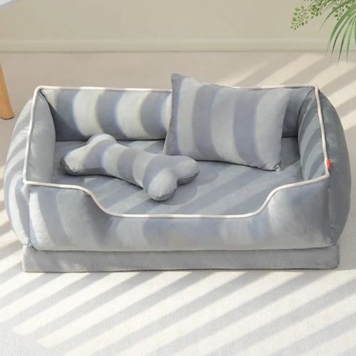 Un canapé chien gris orthopédique avec deux  coussins un coussin rectangle et un autre en forme d'os 
