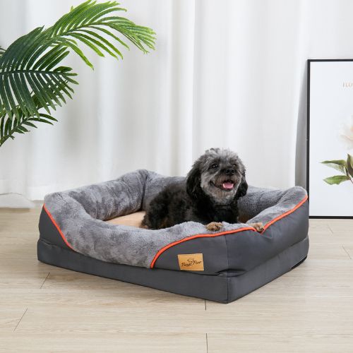 Caniche noir assis sur un canape pour chien gris, spacieux et moelleux. 