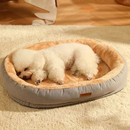 Petit chien blanc endormi sur un coussin pour chien couleur gris, doux et rembourré.