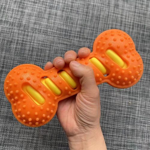 Main pliant un os couineur orange pour démontrer la souplesse du caoutchouc, prouvant que ce jouet chien indestructible absorbe la pression sans se briser.