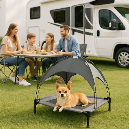 Petit chien allongé confortablement sur un lit de camp pour chien avec toit, installé à l’extérieur près d’un camping-car