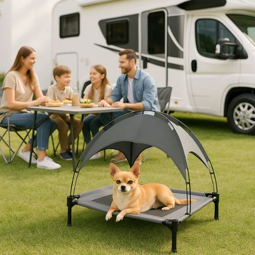 Petit chien allongé confortablement sur un lit de camp pour chien avec toit, installé à l’extérieur près d’un camping-car