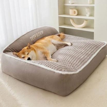 Chien Shiba endormi sur un lit pour chien gris orthopédique avec dossier pour confort optimal