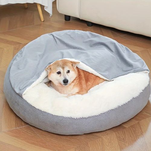 Panier chien apaisant gris doux et rembourré avec un chien Shiba Inu à l’intérieur, posé dans un coin lumineux.