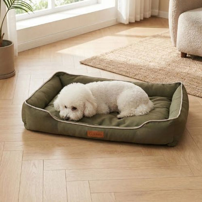 Un caniche blanc allongé dans un panier pour chien vert confortable et résistant, intérieur doux et rebords sécurisants, idéal pour repos et détente.