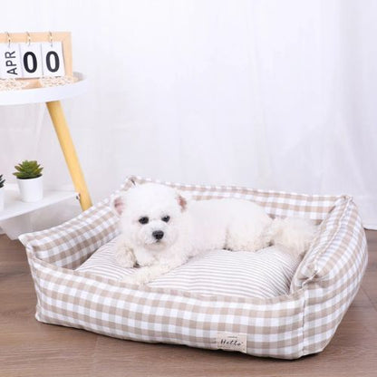 Petit chien couché dans un panier pour chien moelleux en tissu vichy beige, placé dans un intérieur lumineux