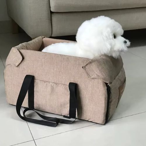 Petit chien assis dans un lit pour chien auto beige, sécurisé et confortable, utilisé lors d’un trajet en voiture.