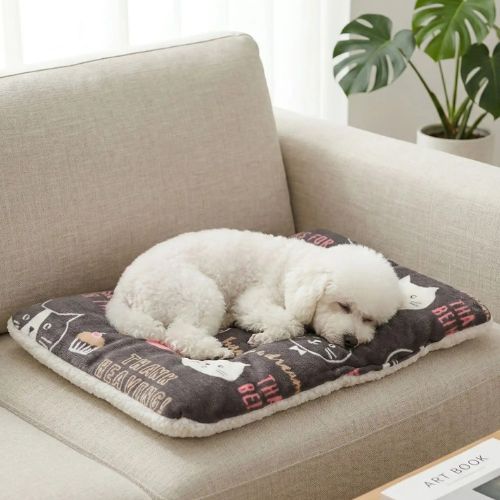 Un Caniche blanc allongé sur un tapis pour chien marron doux au toucher format rectangulaire.